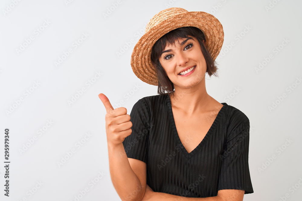Young beautiful woman wearing black t-shirt and hat standing over isolated white background happy with big smile doing ok sign, thumb up with fingers, excellent sign Young beautiful woman wearing black t-shirt and hat standing over isolated white background happy with big smile doing ok sign, thumb up with fingers, excellent sign