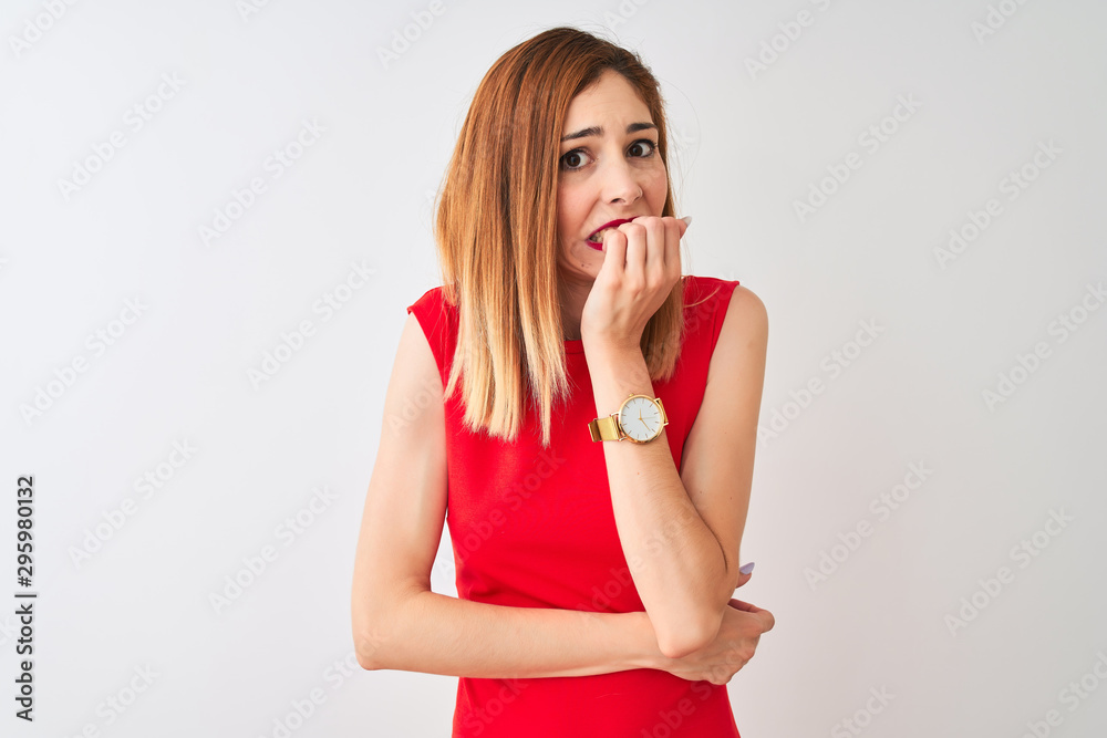 Redhead businesswoman wearing elegant red dress standing over isolated white background looking stressed and nervous with hands on mouth biting nails. Anxiety problem. Redhead businesswoman wearing elegant red dress standing over isolated white background looking stressed and nervous with hands on mouth biting nails. Anxiety problem.