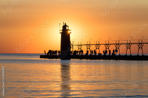 sunset behind lighthouse with silhouettes of people