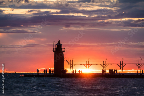 lighthouse at sunset with silhouetted people