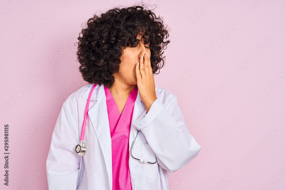 Young arab doctor woman with curly hair wearing stethoscope over isolated pink background bored yawning tired covering mouth with hand. Restless and sleepiness. Young arab doctor woman with curly hair wearing stethoscope over isolated pink background bored yawning tired covering mouth with hand. Restless and sleepiness.