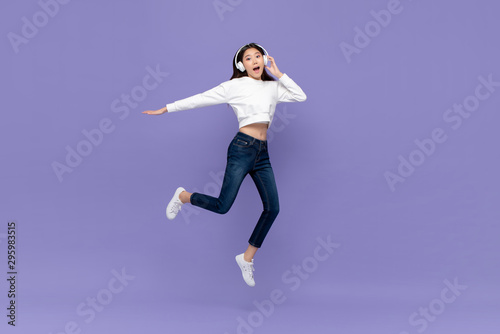 Fototapeta Naklejka Na Ścianę i Meble -  Asian woman jumping and listening to music on headphones