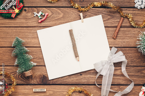Top view of blank notebook on wood background with xmas decorations. Mockup Christmas background with notebook for wish list or to do list. Flat lay with copy space.