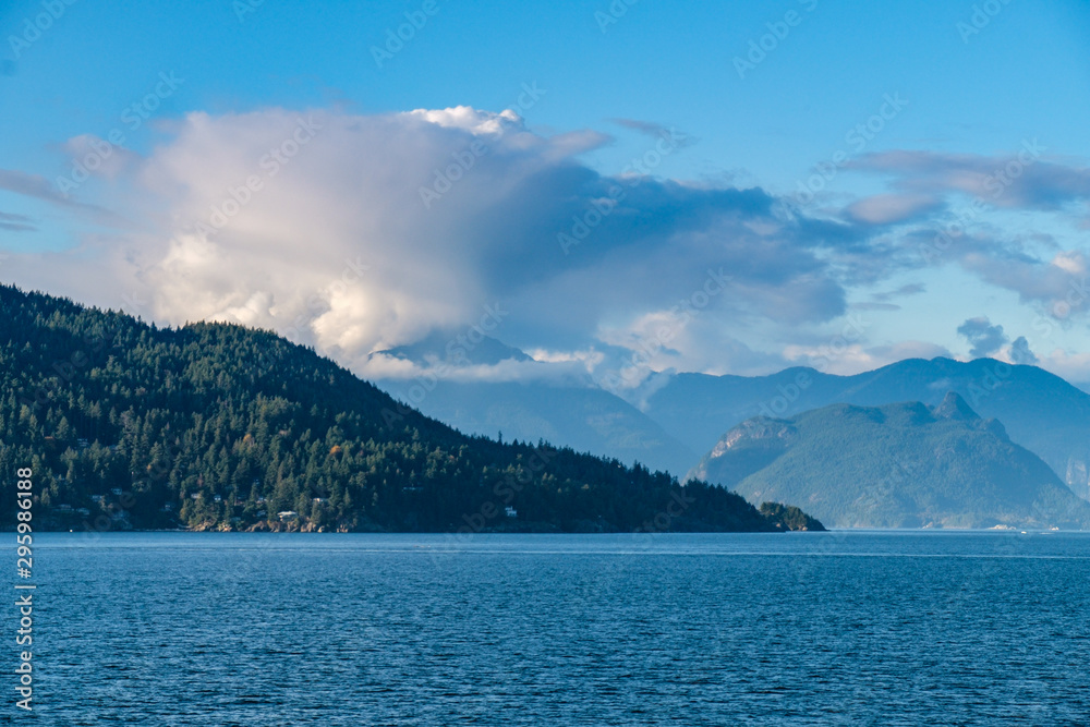 dense cloud with beautiful shape above the mountains of forest covered islands by the blue ocean on a sunny afternoon dense cloud with beautiful shape above the mountains of forest covered islands by the blue ocean on a sunny afternoon