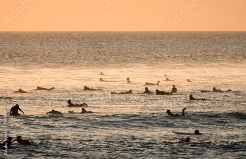 Surfers wait for waves at sunset on Canggu beach, Bali, Indonesia 