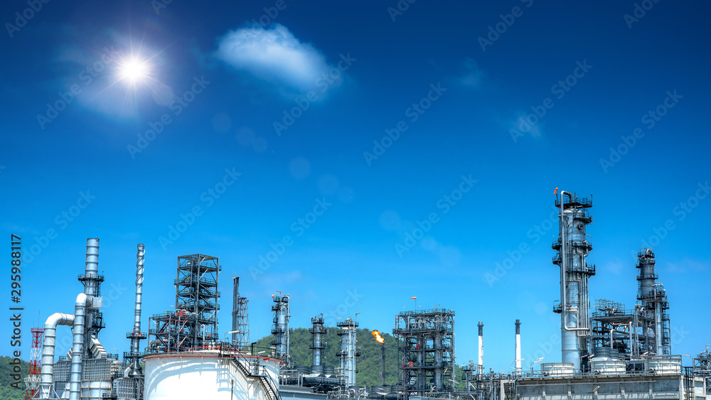Fototapeta premium Oil and gas industrial refinery zone,Detail of equipment oil pipeline steel with valve from large oil storage tank at cloudy sky. -image