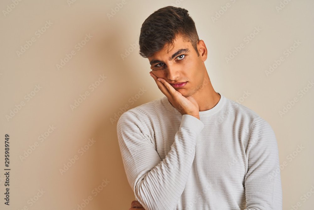 Young indian man wearing sweater standing over isolated white background thinking looking tired and bored with depression problems with crossed arms. Young indian man wearing sweater standing over isolated white background thinking looking tired and bored with depression problems with crossed arms.