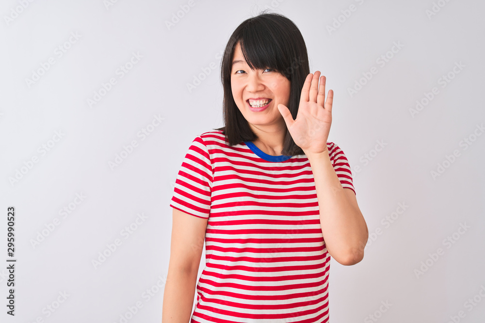 Young beautiful chinese woman wearing red striped t-shirt over isolated white background Waiving saying hello happy and smiling, friendly welcome gesture Young beautiful chinese woman wearing red striped t-shirt over isolated white background Waiving saying hello happy and smiling, friendly welcome gesture