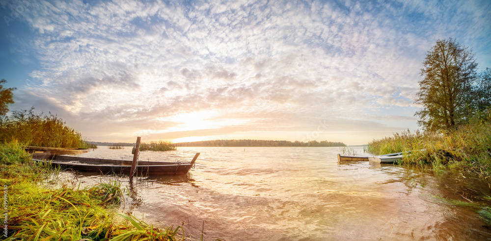 Fototapeta premium Panoramic landscape with sunrise in a water body with boats