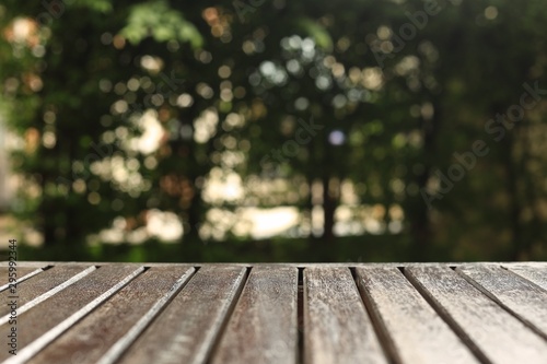 wooden floor background for products placement copy space. wood table in a garden. forest bokeh light background. warm tone image