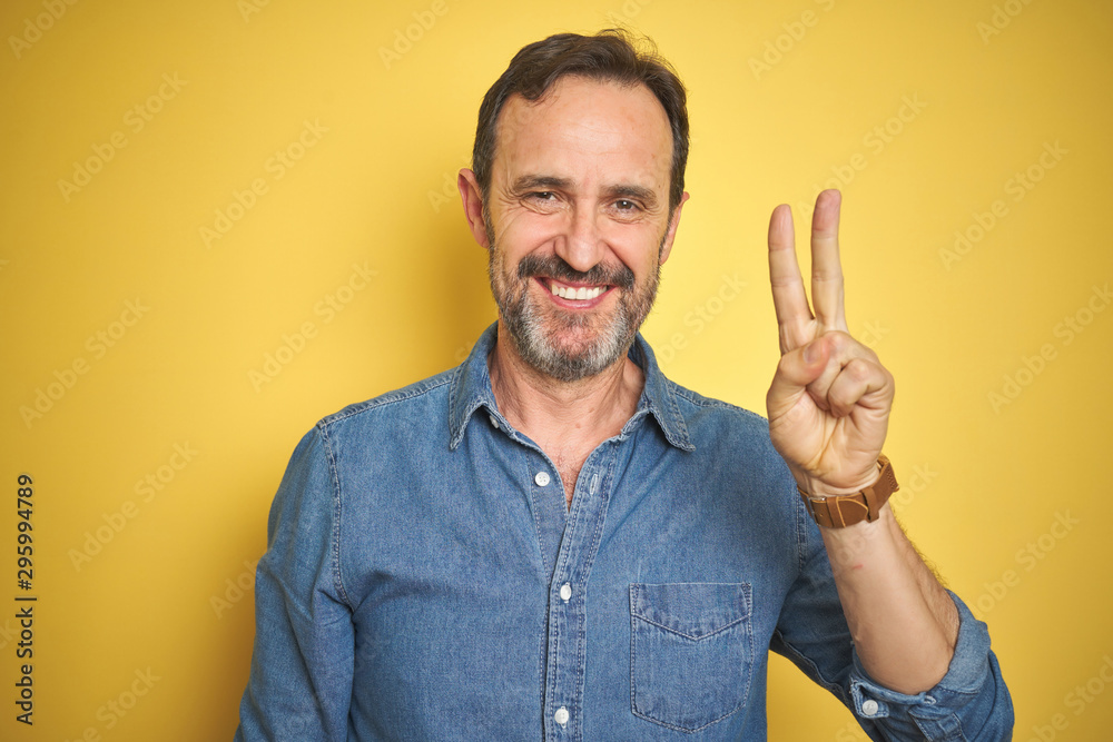 Handsome middle age senior man with grey hair over isolated yellow background showing and pointing up with fingers number two while smiling confident and happy. Handsome middle age senior man with grey hair over isolated yellow background showing and pointing up with fingers number two while smiling confident and happy.
