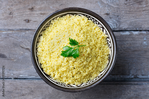 Couscous in bowl. Wooden background. Close up. Top view.