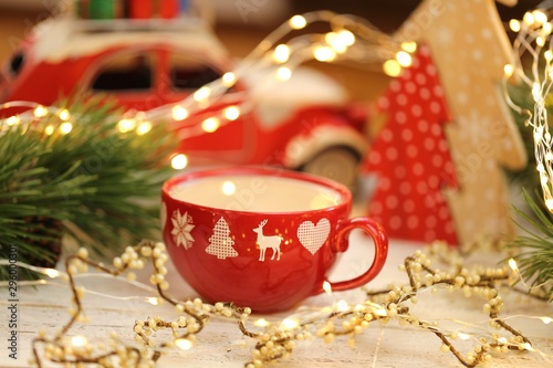 Christmas time. Christmas tea in a red cup,  decorative machine, red wooden tree, vintage garland on shabby chic background.Winter holidays.