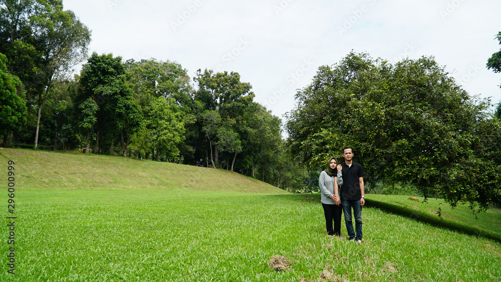 Young beautiful muslim couple standing together natural background.