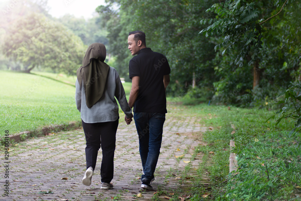 Fototapeta premium Young beautiful muslim couple hand by hand walking on natural background