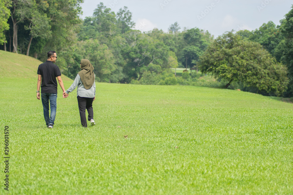 Young playful young muslim Asian couple running together hand by hand on natural background Young playful young muslim Asian couple running together hand by hand on natural background