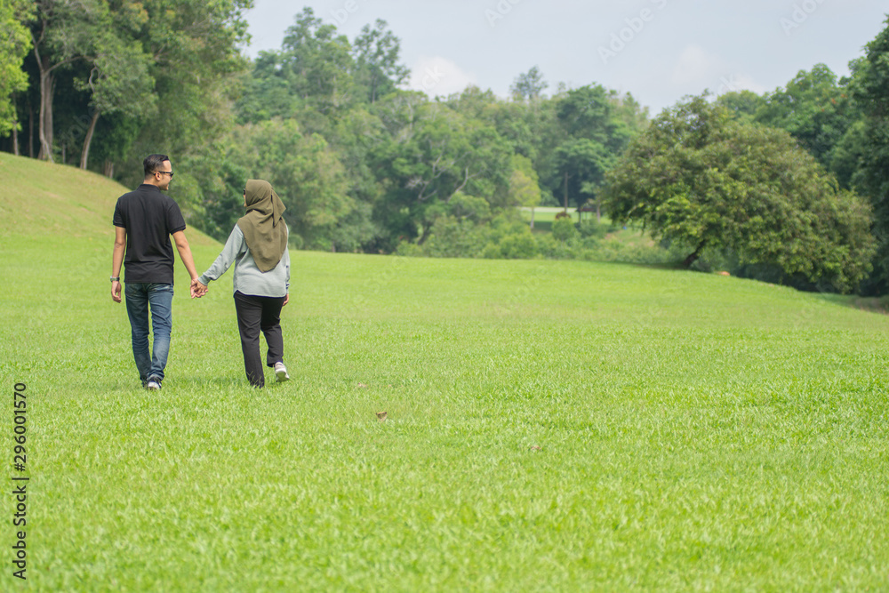 Young playful young muslim Asian couple  running together hand by hand on natural background