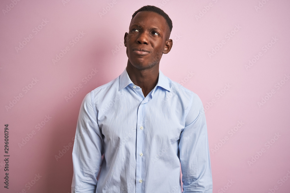 African american man wearing blue elegant shirt standing over isolated pink background smiling looking to the side and staring away thinking. African american man wearing blue elegant shirt standing over isolated pink background smiling looking to the side and staring away thinking.