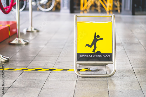 Photography yellow beware of uneven floor sign board on tile floor