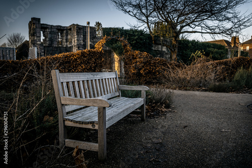 YORK, ENGLAND, DECEMBER 12, 2018: Wooden bench in an old park full of dry leaves. Concept of tranquility and peaceful moment.
