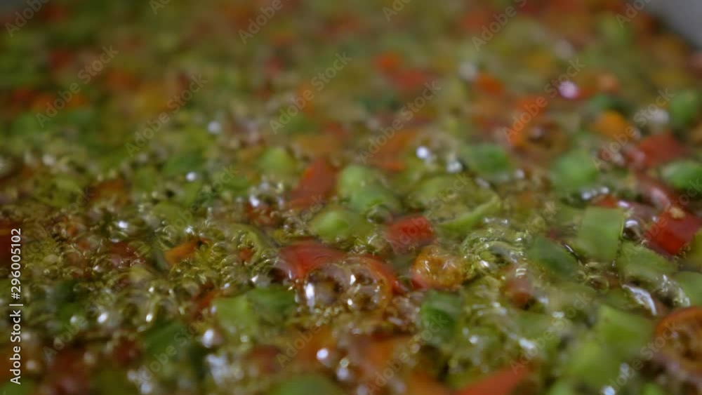 Macro Shot of red and green chopped chilli peppers frying in a pan. 4K video Macro Shot of red and green chopped chilli peppers frying in a pan. 4K video