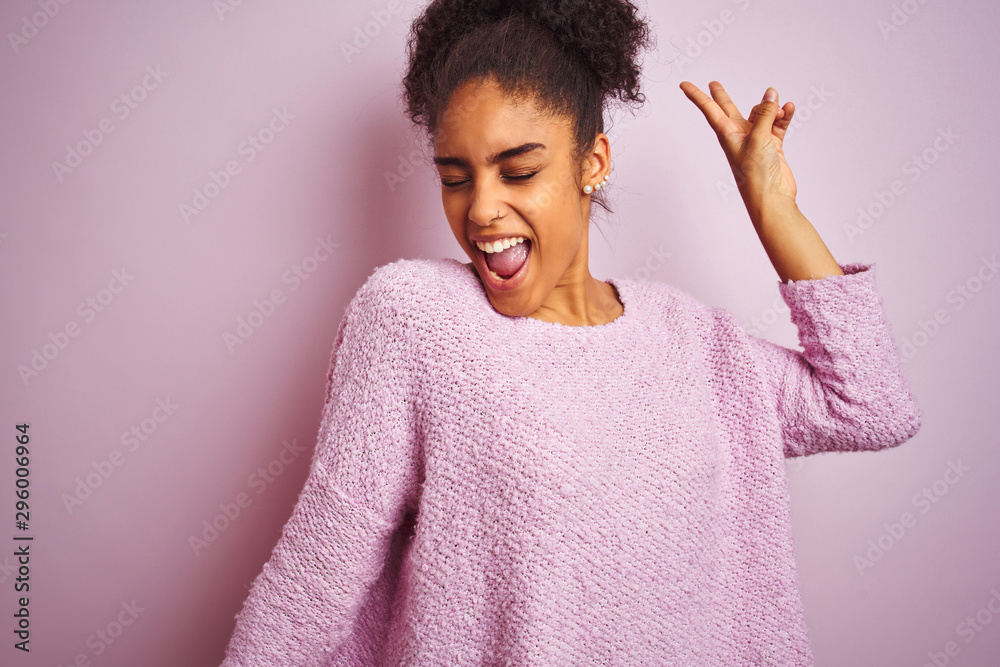 Young african american woman wearing winter sweater standing over isolated pink background Dancing happy and cheerful, smiling moving casual and confident listening to music Young african american woman wearing winter sweater standing over isolated pink background Dancing happy and cheerful, smiling moving casual and confident listening to music