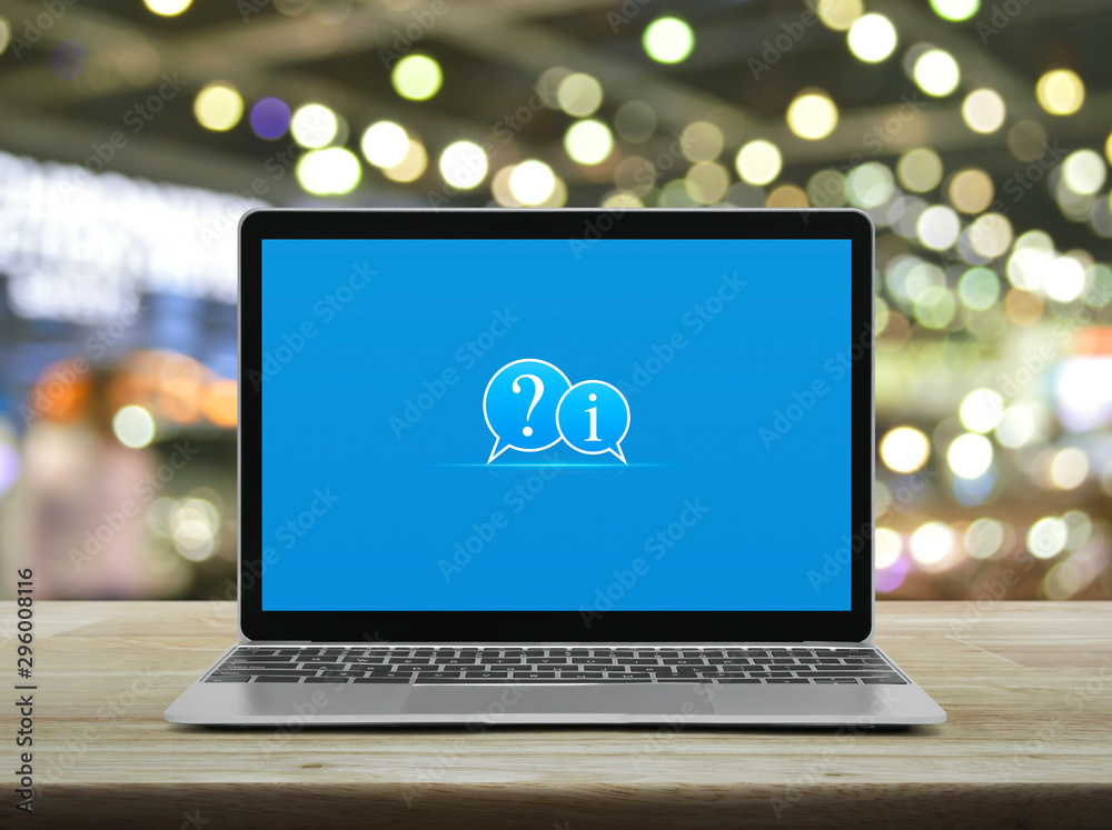 Question mark and information chat icon with modern laptop computer on wooden table over blur light and shadow of shopping mall, Business customer support online concept Question mark and information chat icon with modern laptop computer on wooden table over blur light and shadow of shopping mall, Business customer support online concept