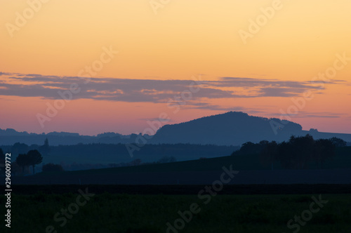 Mount Spitzberg Oberoderwitz in the Lusatian Mountains during blue hour against sunset sky with few clouds