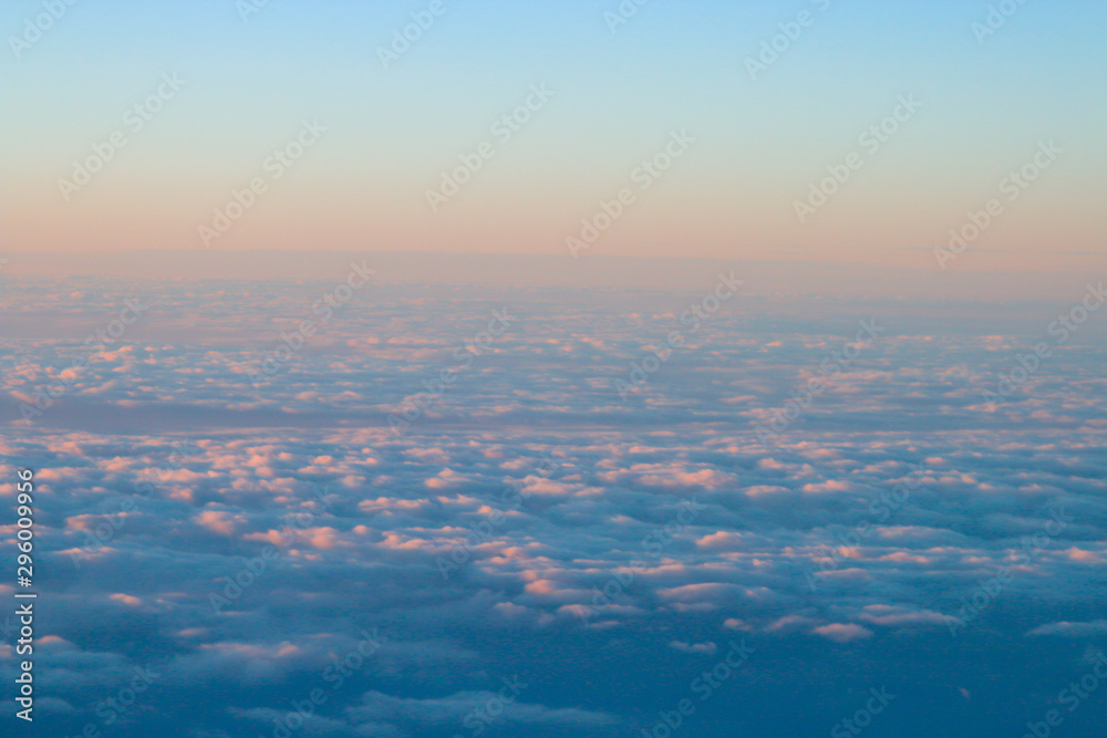 Un mar de nubes con los colores cálidos del atardecer. Fotografía desde un avión.