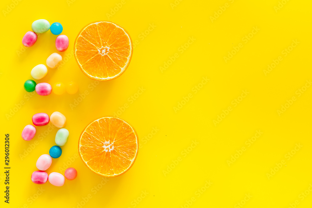 Sweet New Year design. 2020 laid out with candy and oranges on yellow background top view space for text Sweet New Year design. 2020 laid out with candy and oranges on yellow background top view space for text