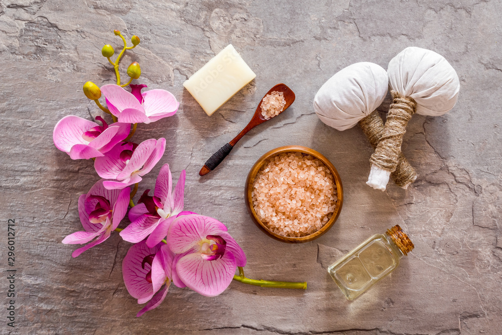 Massage table with thai herbal balls and orchids on grey background top view pattern Massage table with thai herbal balls and orchids on grey background top view pattern
