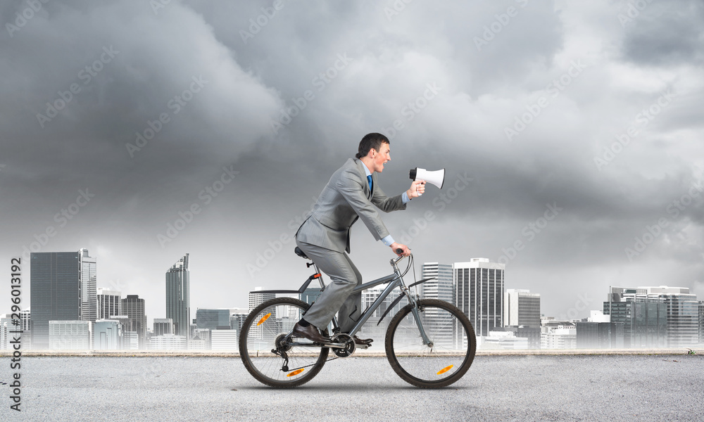 Obraz premium Businessman with megaphone in hand on bike