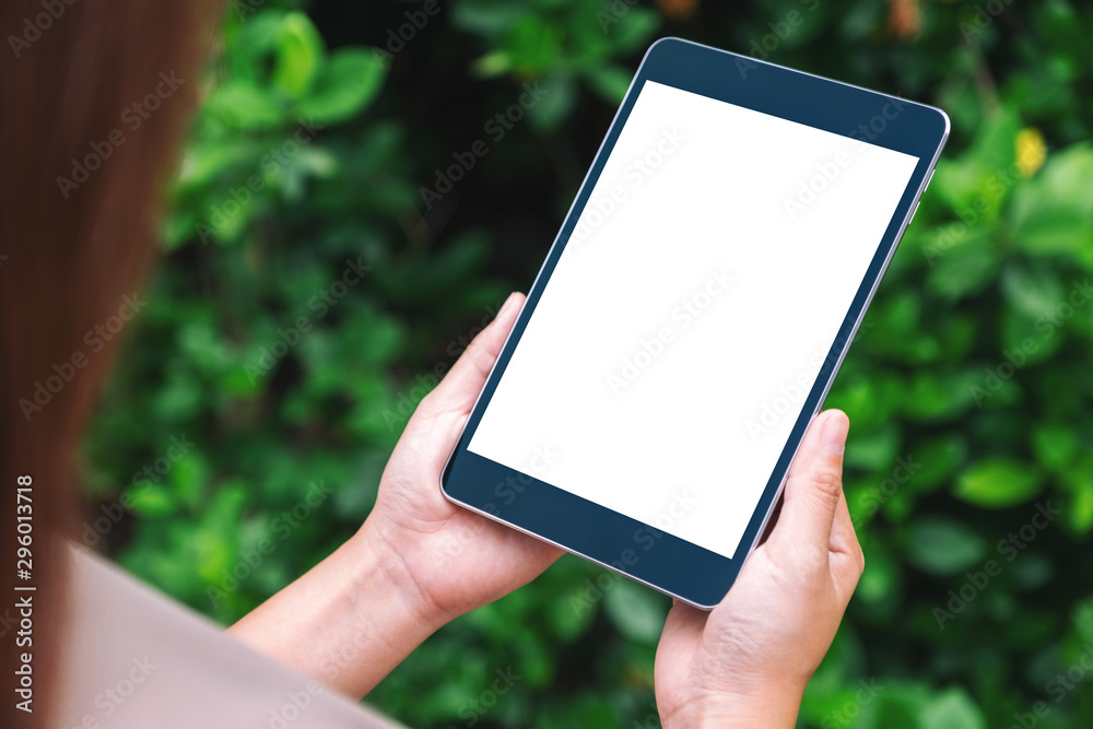 Mockup image of a woman holding black tablet pc with blank white desktop screen in the park Mockup image of a woman holding black tablet pc with blank white desktop screen in the park