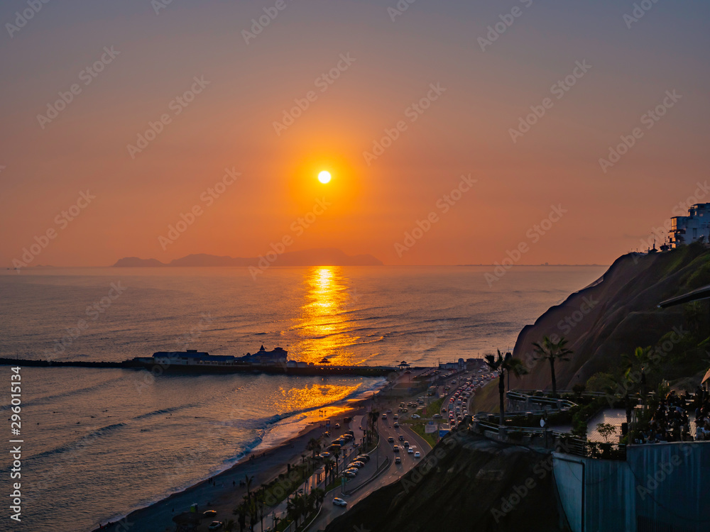 Sunset in the coast of Miraflores district. Reddish sun sets behind the sea. Lima city, Peru Sunset in the coast of Miraflores district. Reddish sun sets behind the sea. Lima city, Peru