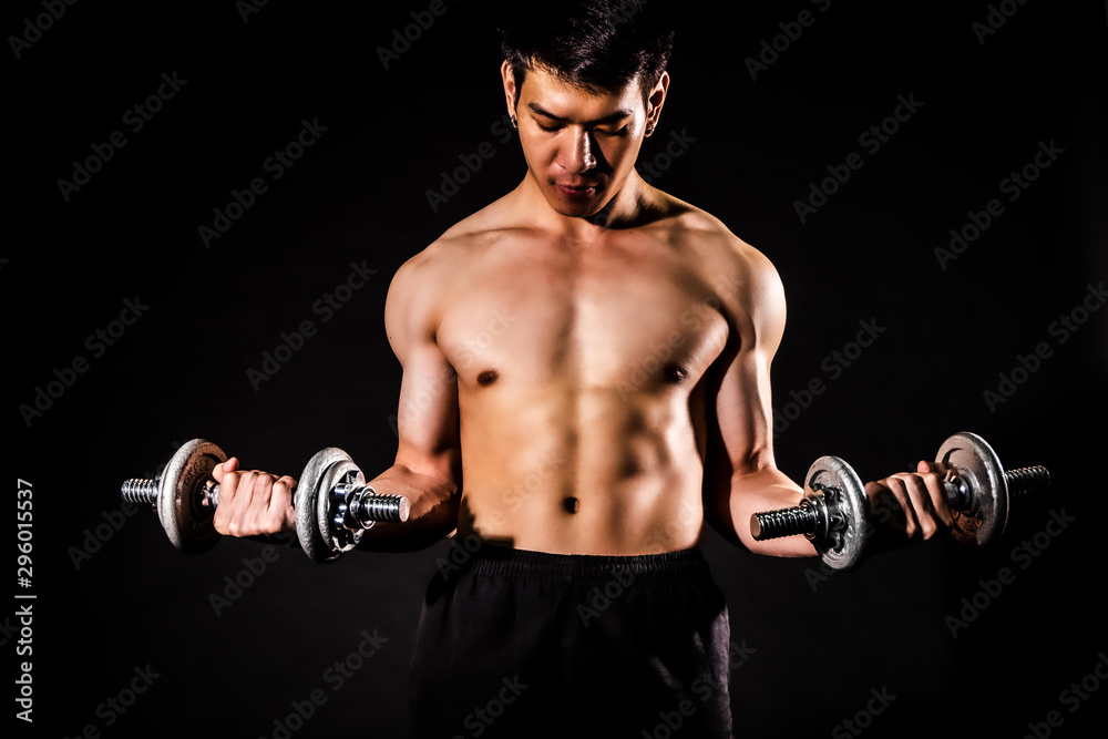 sport man standing holding a towel and bottled water and showing muscle bodybuilding on black backgrounds, fitness concept, sport concept