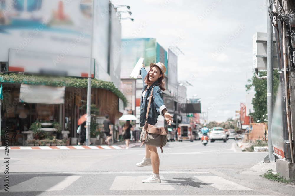 Smiling woman traveler in thapae gate landmark chiangmai thailand with backpack holding world map on holiday, relaxation concept, travel concept