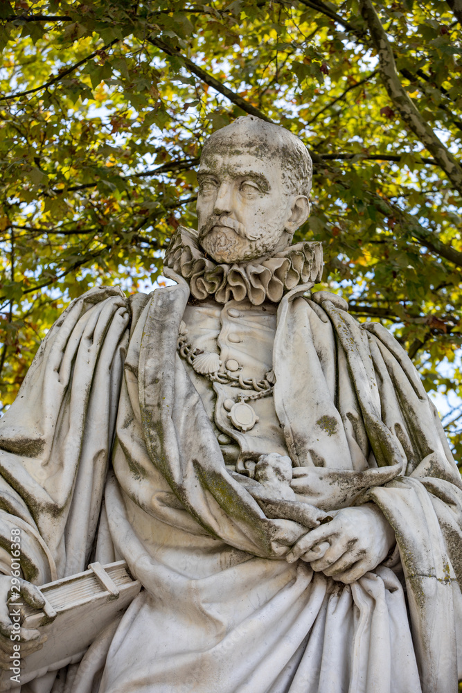 Statue of Michel de Montaigne in public garden along Place des Quinconces, Bordeaux France, with a canopy of green trees.