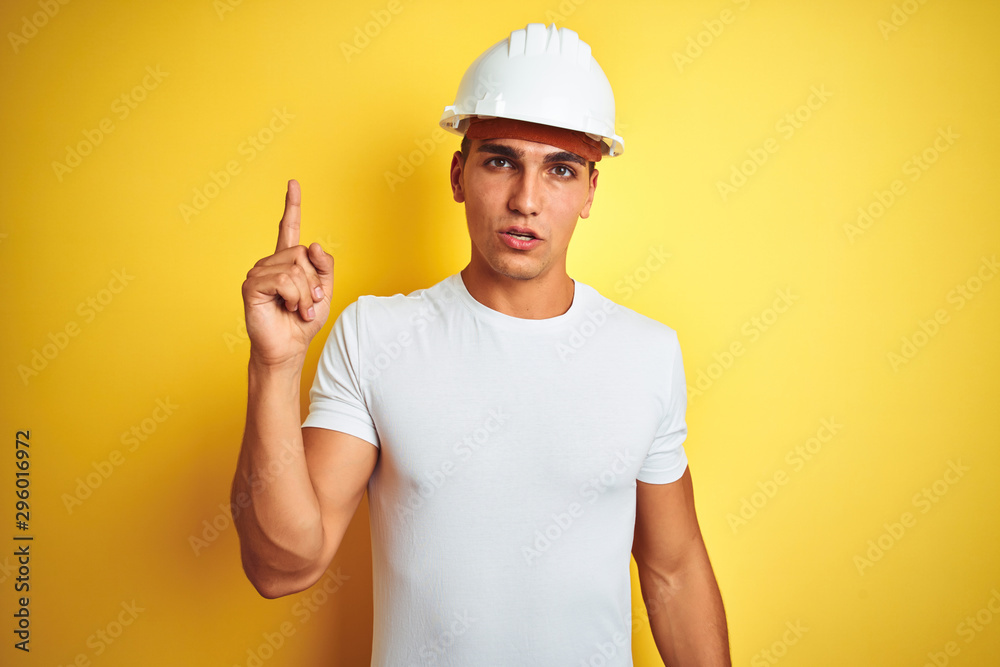 Young handsome man wearing construction helmet over yellow isolated background pointing finger up with successful idea. Exited and happy. Number one. Young handsome man wearing construction helmet over yellow isolated background pointing finger up with successful idea. Exited and happy. Number one.