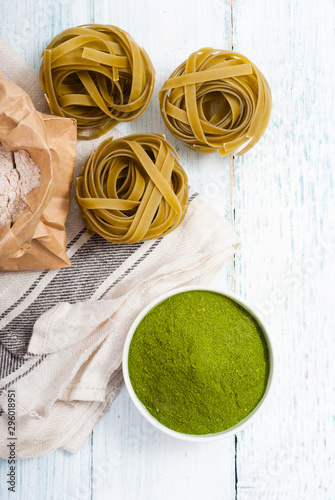 uncooked taglatelle pasta and ingredients: grounded spinach powder and whole wheat flour photo