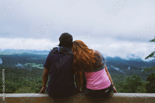 Couple sitting in front of a mountain looking at the horizon in the holiday. Travel relax. Sitting relax on the Moutain rock cliff. Nature of mountain forests in Thailand.