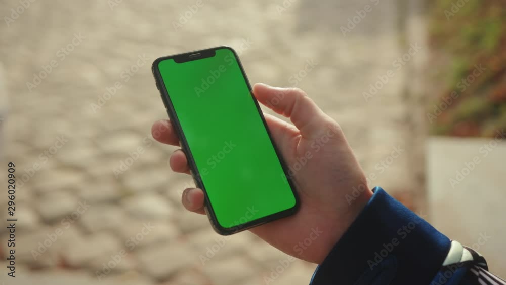 Close up young hand man using phone with vertical green screen on sunlight blurred background internet chrome outdoor cellular isolate message smartphone scrolling tapping communication slow motion Close up young hand man using phone with vertical green screen on sunlight blurred background internet chrome outdoor cellular isolate message smartphone scrolling tapping communication slow motion