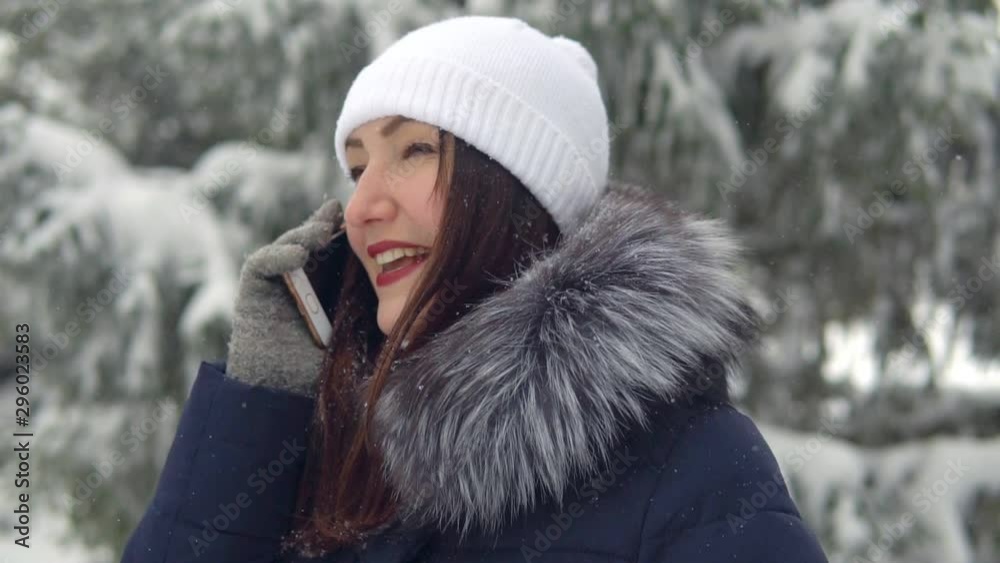 Young woman is talking on the phone in the winter forest, slow motion. Walk in the fresh air. Young woman is talking on the phone in the winter forest, slow motion. Walk in the fresh air.