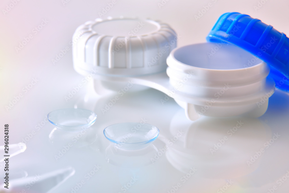 Contact lenses and case reflected on white glass table Contact lenses and case reflected on white glass table