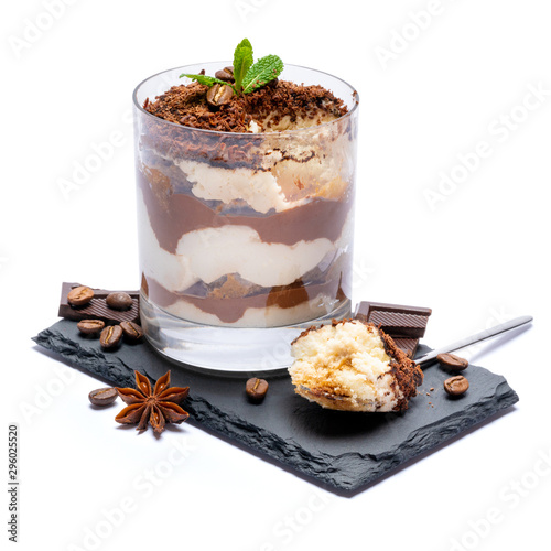 Classic tiramisu dessert in a glass cup and pieces of chocolate on stone cutting board on white background with clipping path