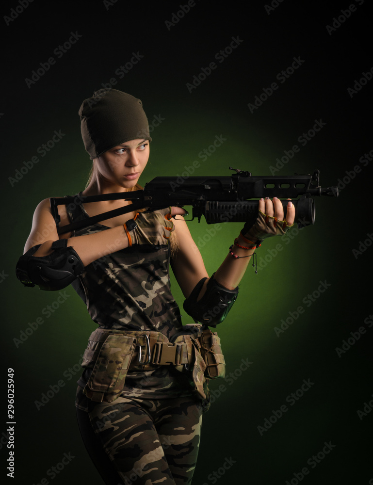 the girl in military overalls airsoft posing with a gun in his hands on a dark background in the haze the girl in military overalls airsoft posing with a gun in his hands on a dark background in the haze