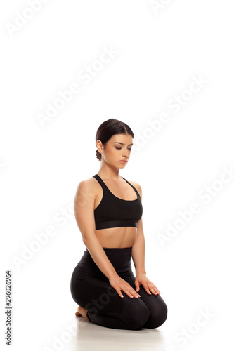 Young yoga woman is sitting in yoga diamond pose, relaxing. Isolated on white background. 