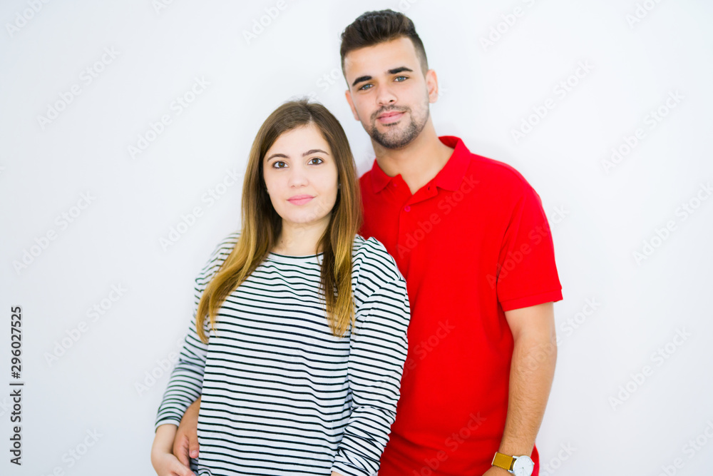 Young beautiful couple together over white isolated background with serious expression on face. Simple and natural looking at the camera. Young beautiful couple together over white isolated background with serious expression on face. Simple and natural looking at the camera.