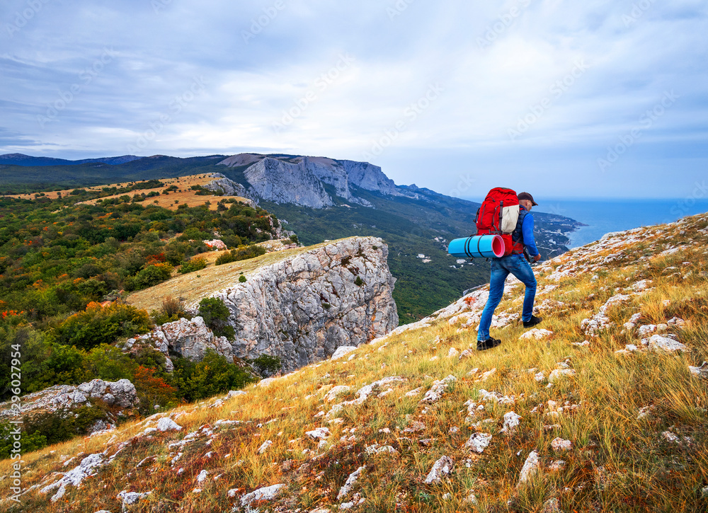 Hiker with a backpack walks in the the mountains near the sea. Crimea in autumn