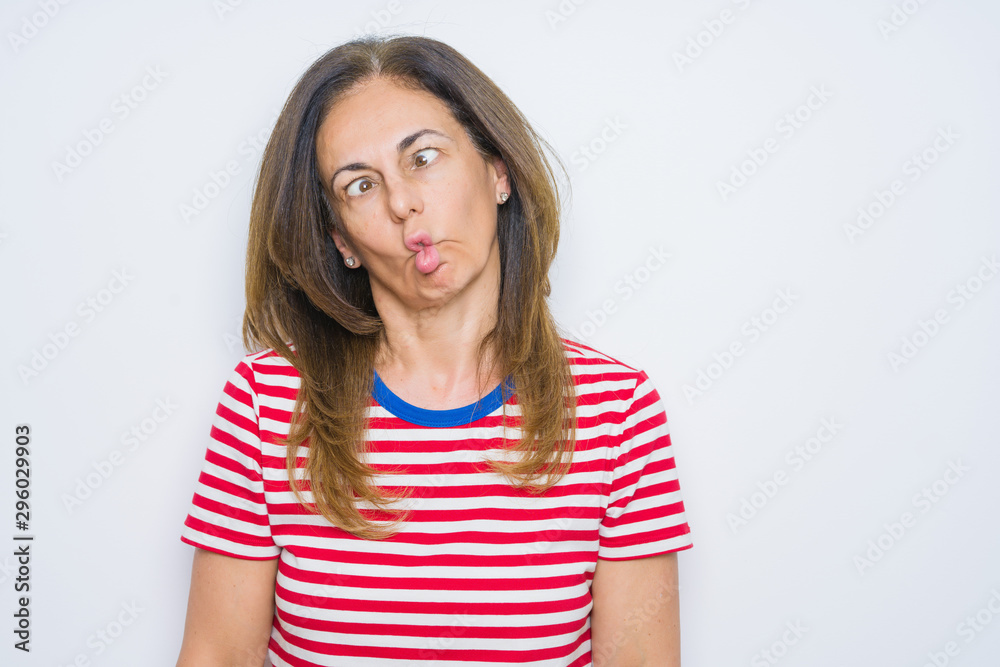 Middle age senior woman standing over white isolated background making fish face with lips, crazy and comical gesture. Funny expression. Middle age senior woman standing over white isolated background making fish face with lips, crazy and comical gesture. Funny expression.