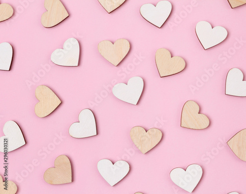 Creative holiday background made from wooden hearts on pastel pink backdrop